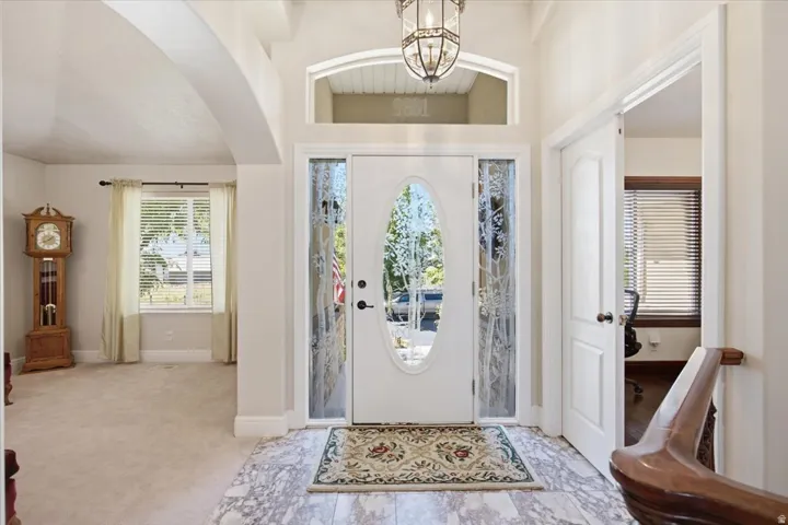 Entryway featuring a decorative transom window, an oval glass front door, decorative sidelight windows, and marble-look flooring