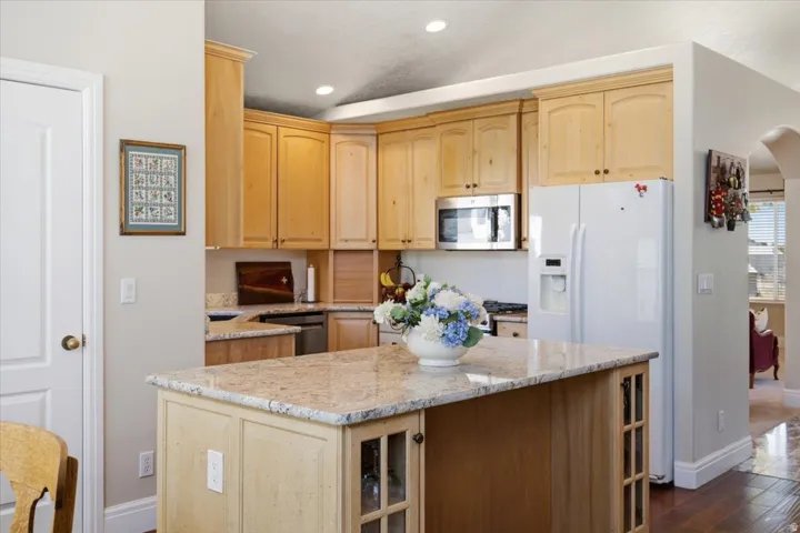 Kitchen featuring light wood cabinetry, granite countertops, an undermount sink, stainless steel microwave, and recessed lighting