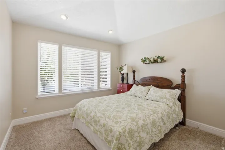 Recessed ceiling lighting, multiple windows with blinds, light-toned carpeting, and neutral wall tones