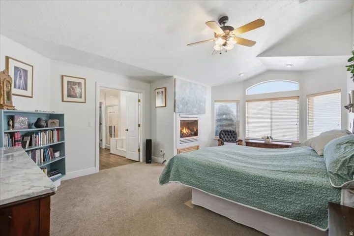 Vaulted ceilings with a ceiling fan, recessed lighting, expansive windows with arch detail, built-in fireplace, and carpeting