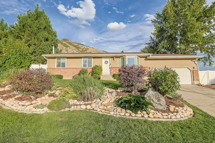 Exterior featuring two-car garage, and a landscaped front yard with decorative rock work
