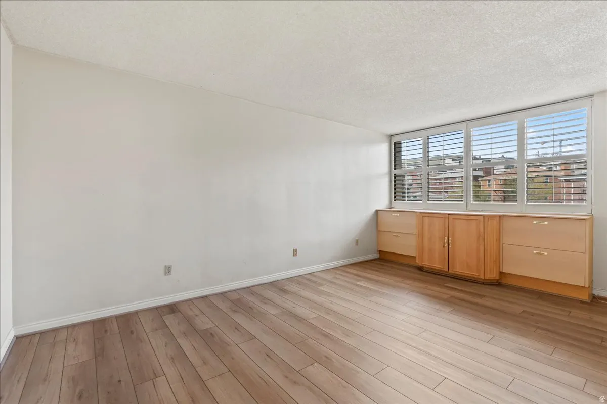 Wood-finish flooring, white walls, and a large window with white plantation shutters