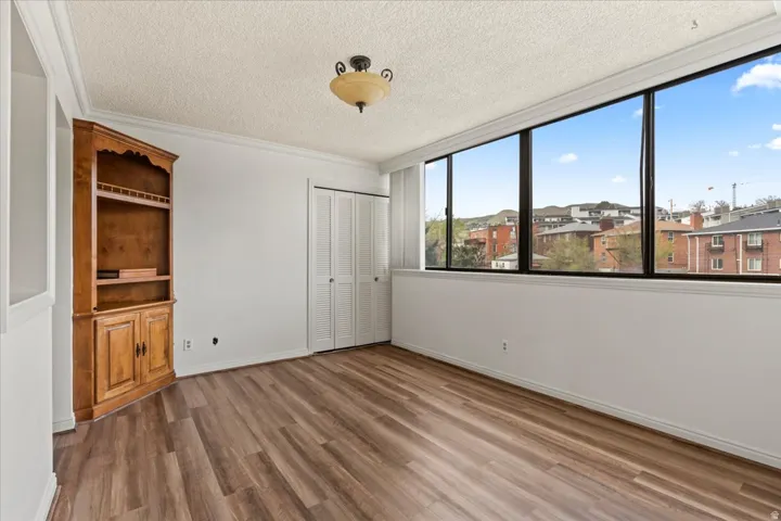 Hardwood-finish flooring, built-in shelving, bi-fold closet doors, crown molding, and expansive windows