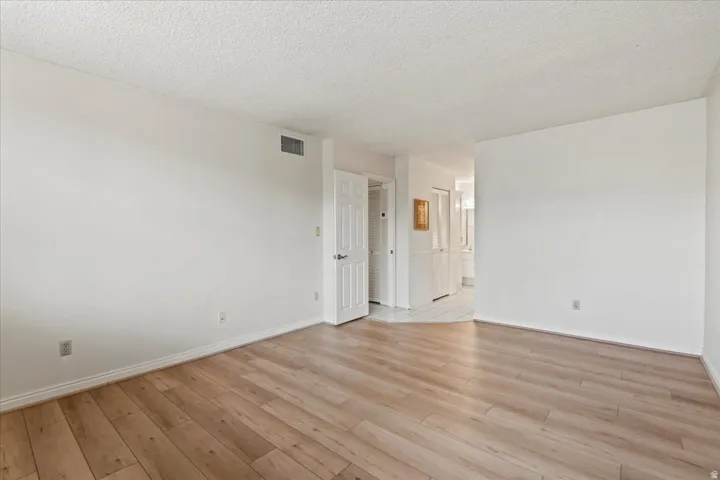 Wood-finish flooring, white painted walls, and textured ceilings