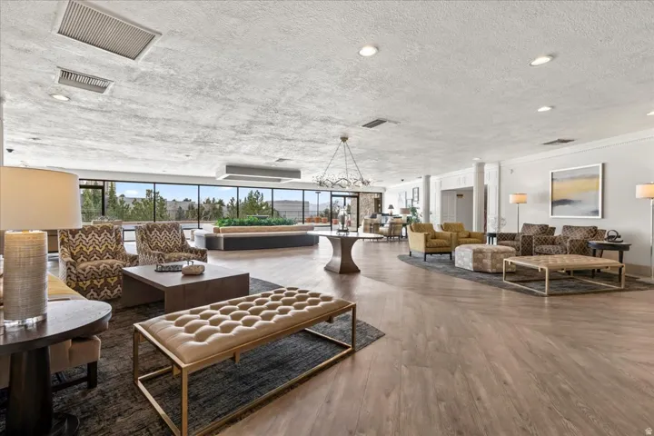 Spacious common area featuring wood-finish flooring, expansive window walls, recessed lighting, and a decorative chandelier