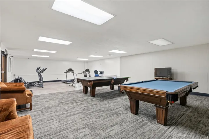 Recreational room featuring two billiard tables, exercise equipment, and recessed lighting