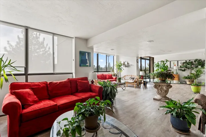 Spacious living area featuring large windows, roller shades, wood-finish flooring, and recessed lighting