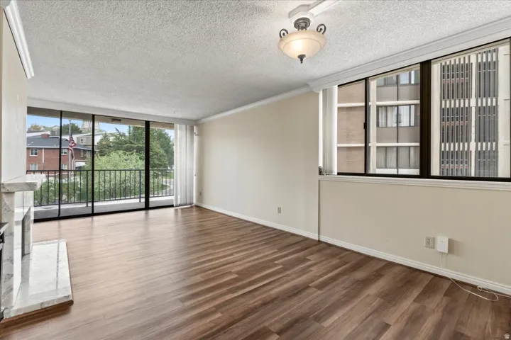Wood-finish flooring throughout, crown molding, and a built-in fireplace with a stone surround