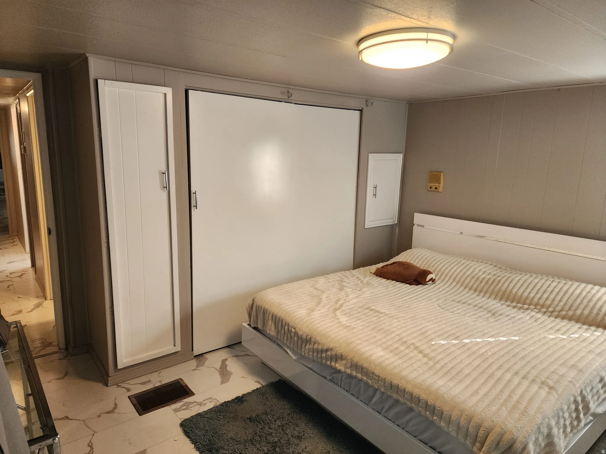 Recessed ceiling lighting illuminates a room featuring a built-in cabinet and a wall-mounted panel