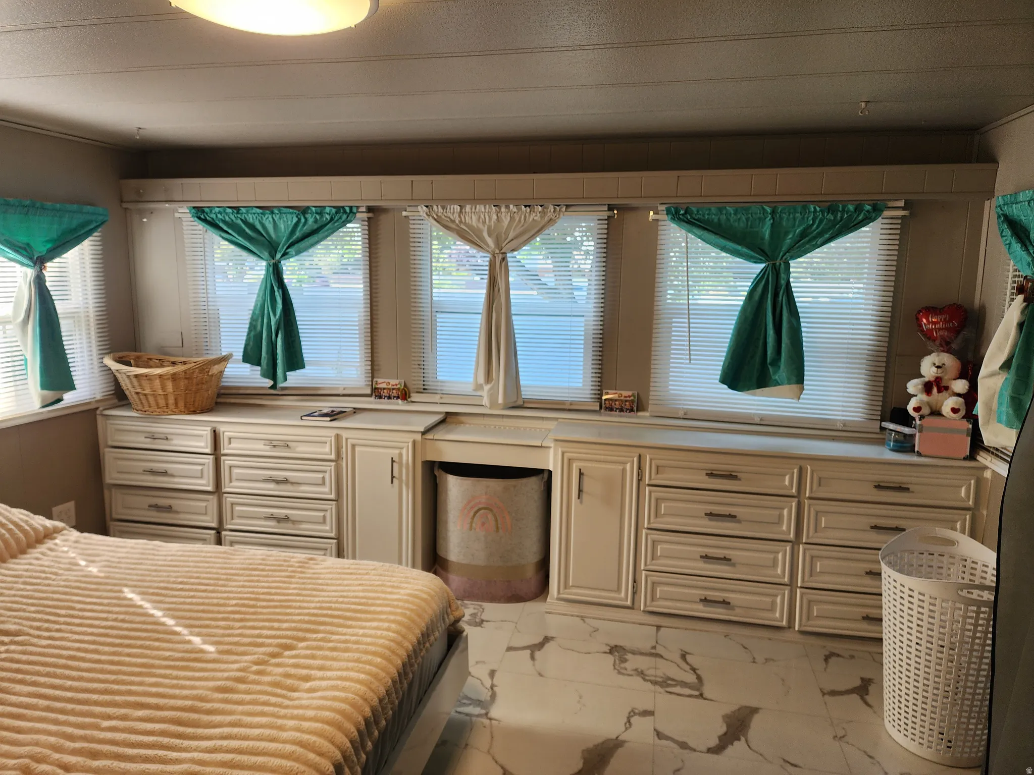 Built-in cabinetry with multiple drawers, expansive countertop surface, and multiple windows with blinds