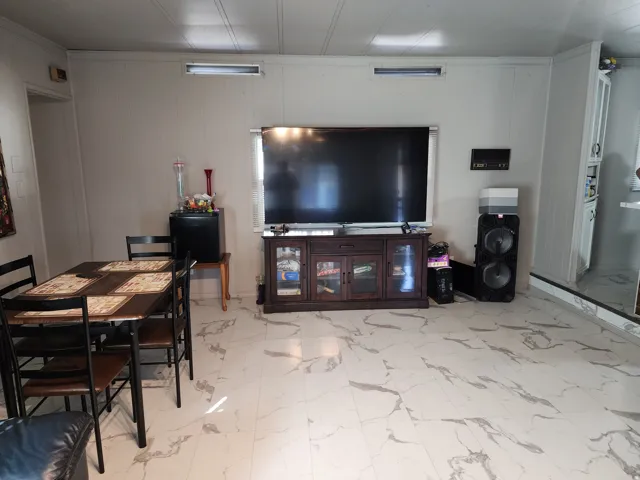 White marble-look flooring throughout, recessed panel walls, and a built-in media console