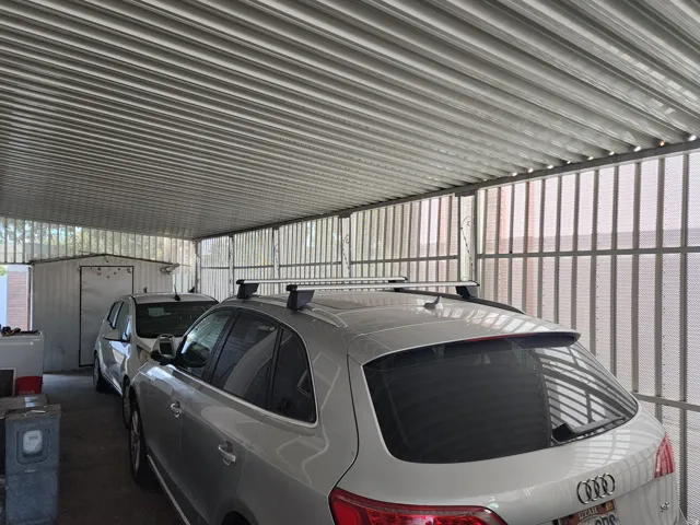 Covered carport with corrugated metal roofing, metal framing, and a storage shed