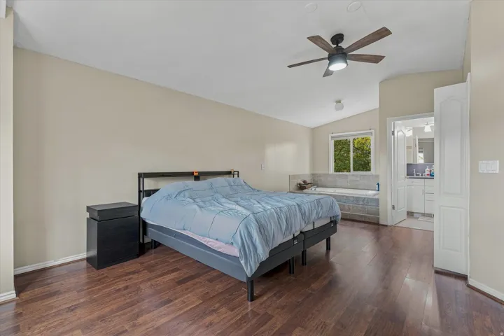 Spacious primary bedroom with wood-finish flooring, neutral wall finishes, and abundant natural light from multiple windows