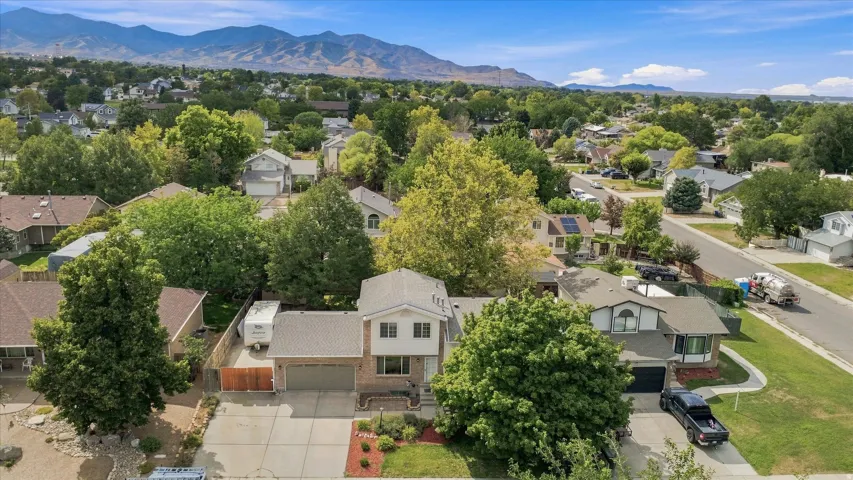 Aerial view showcasing a two-story residence with an attached two-car garage, situated on a landscaped lot with mature trees