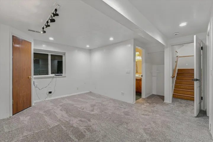 Spacious finished basement featuring neutral carpeting, recessed ceiling lighting, and multiple entry points
