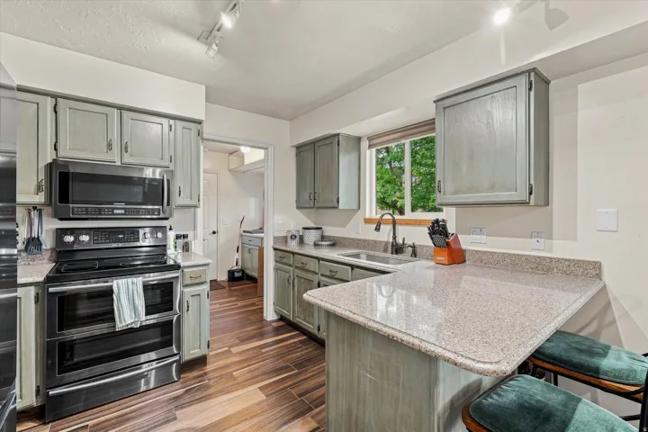Bright, updated kitchen featuring stainless steel double wall ovens, quartz countertops, light gray cabinetry with brushed nickel hardware, and a large island with seating