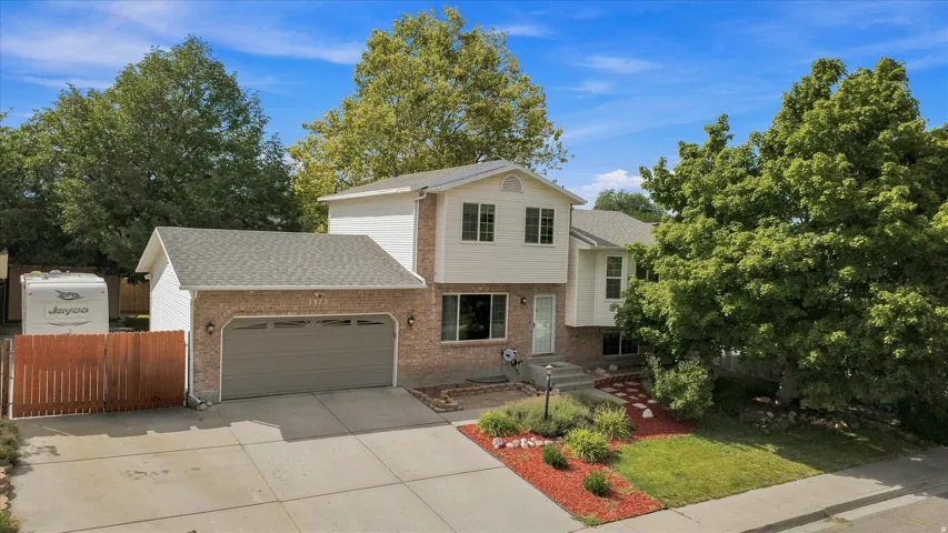 Two-story brick colonial with two-car garage, manicured front lawn, and mature landscaping