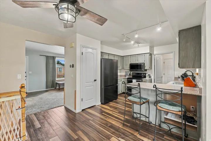 Open-concept kitchen and dining area showcasing wood-finish flooring, stainless steel appliances, a center island with seating, and pendant lighting