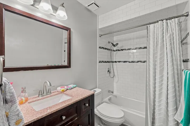 Spa-inspired bathroom featuring a dark wood vanity with a pink stone countertop, recessed lighting, and a large framed mirror