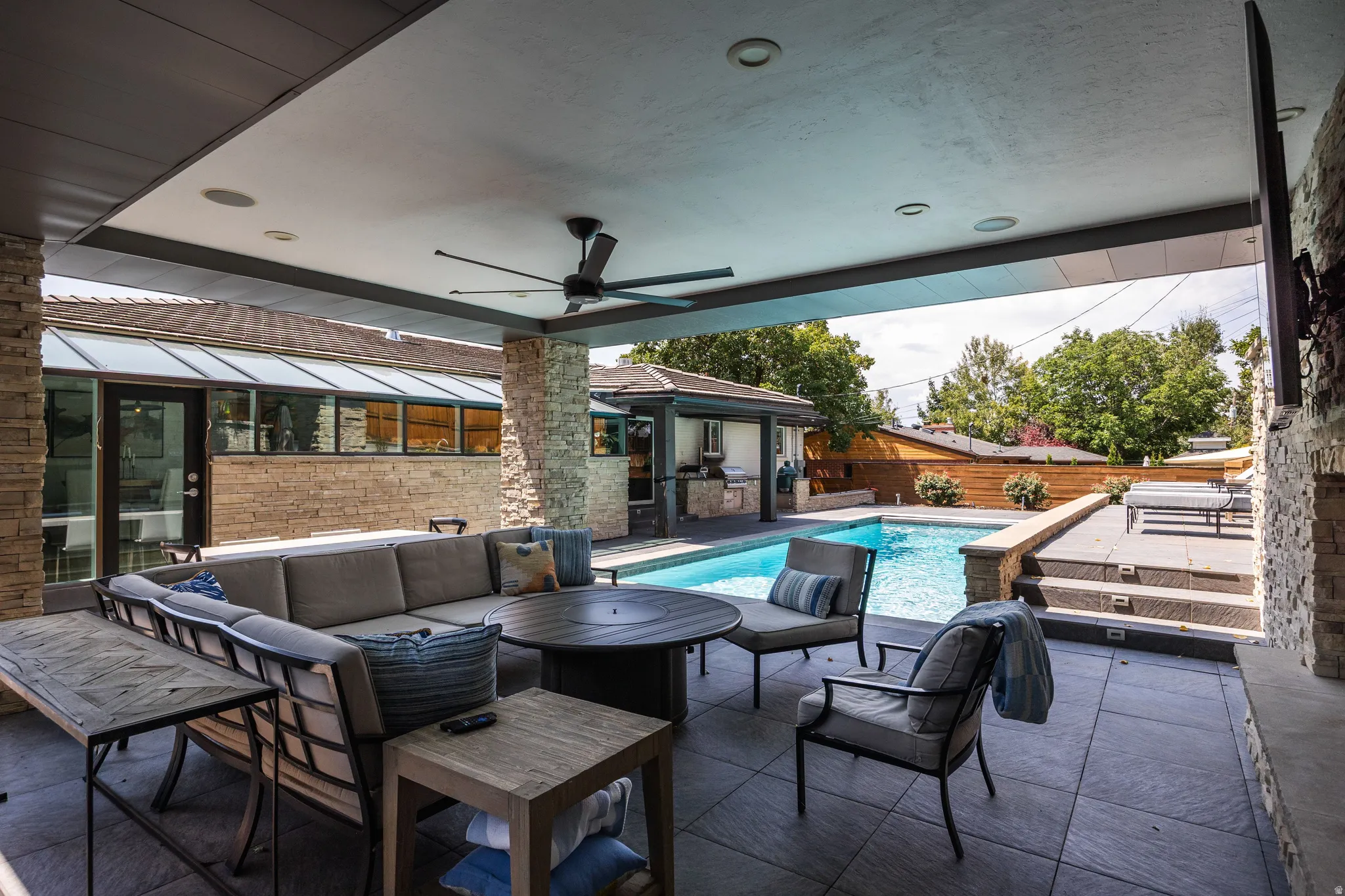 Covered patio featuring stone-clad pillars, recessed lighting, and a ceiling fan