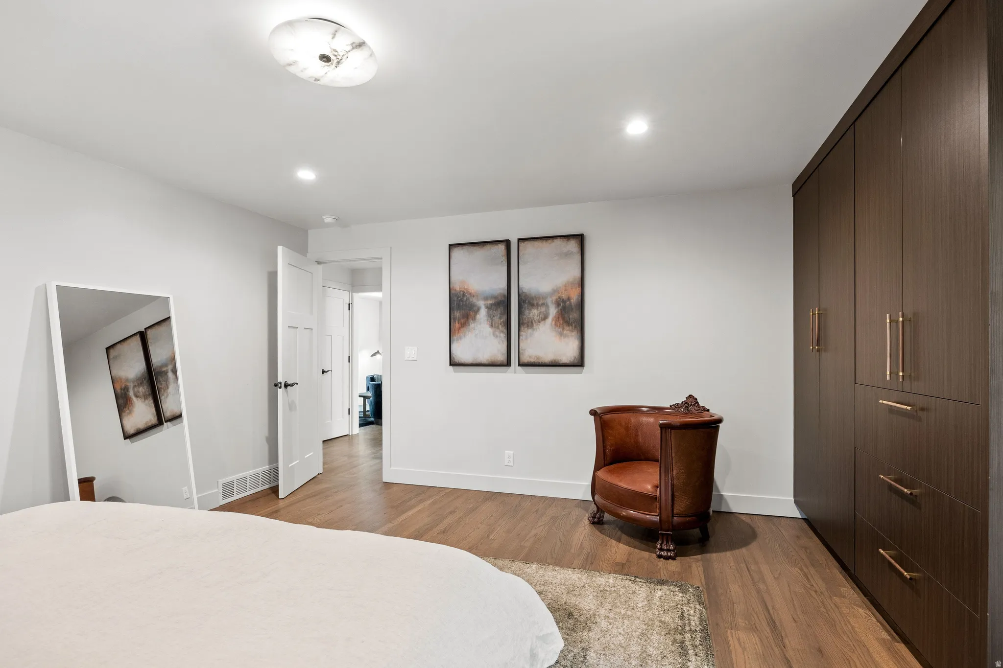 Wood-finish flooring, recessed lighting, built-in cabinetry with modern hardware, and a semi-flush mount ceiling fixture