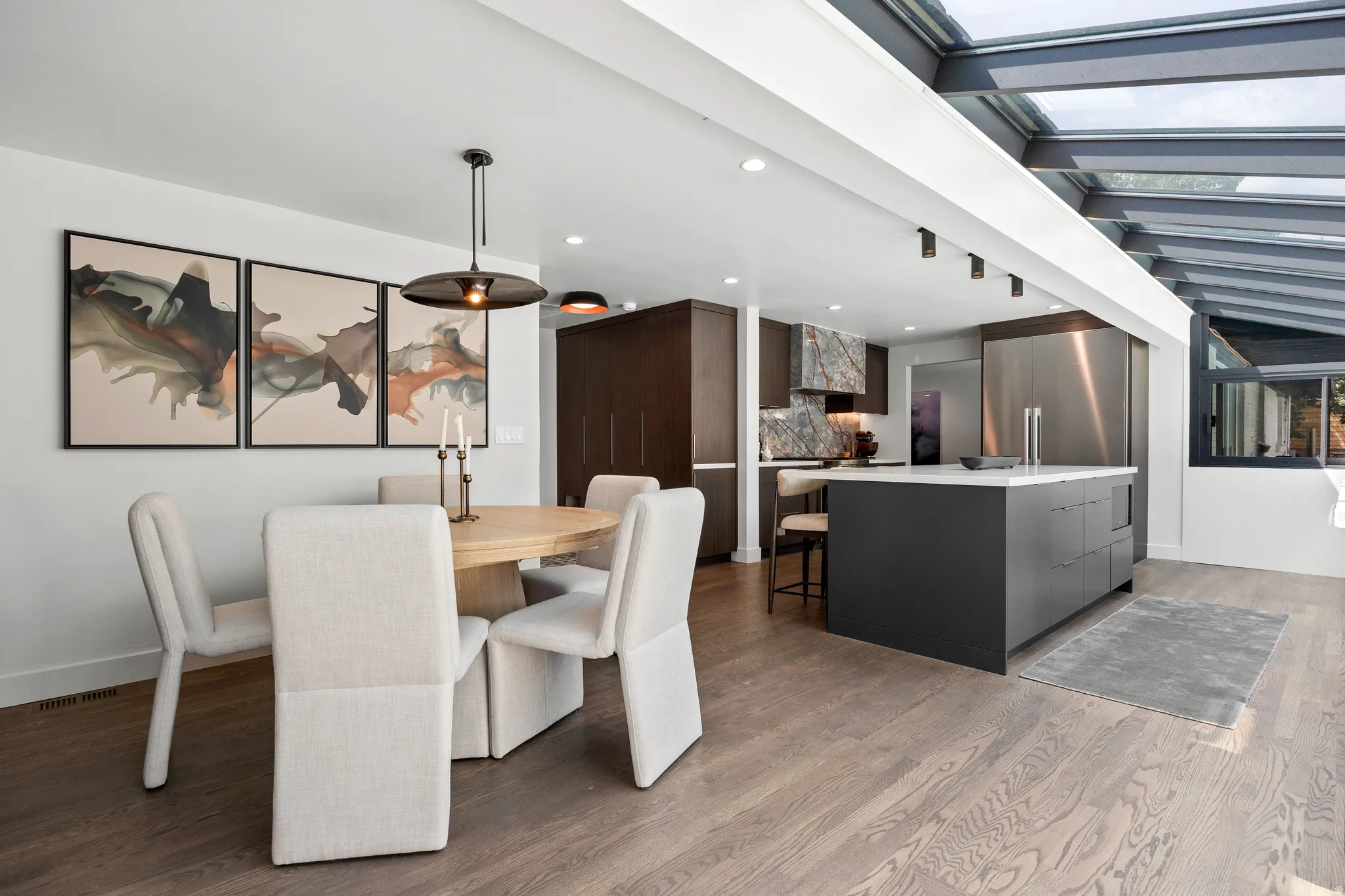 Kitchen with a dark-toned island and light-toned countertop, integrated stainless steel refrigerator, and wood-finish flooring