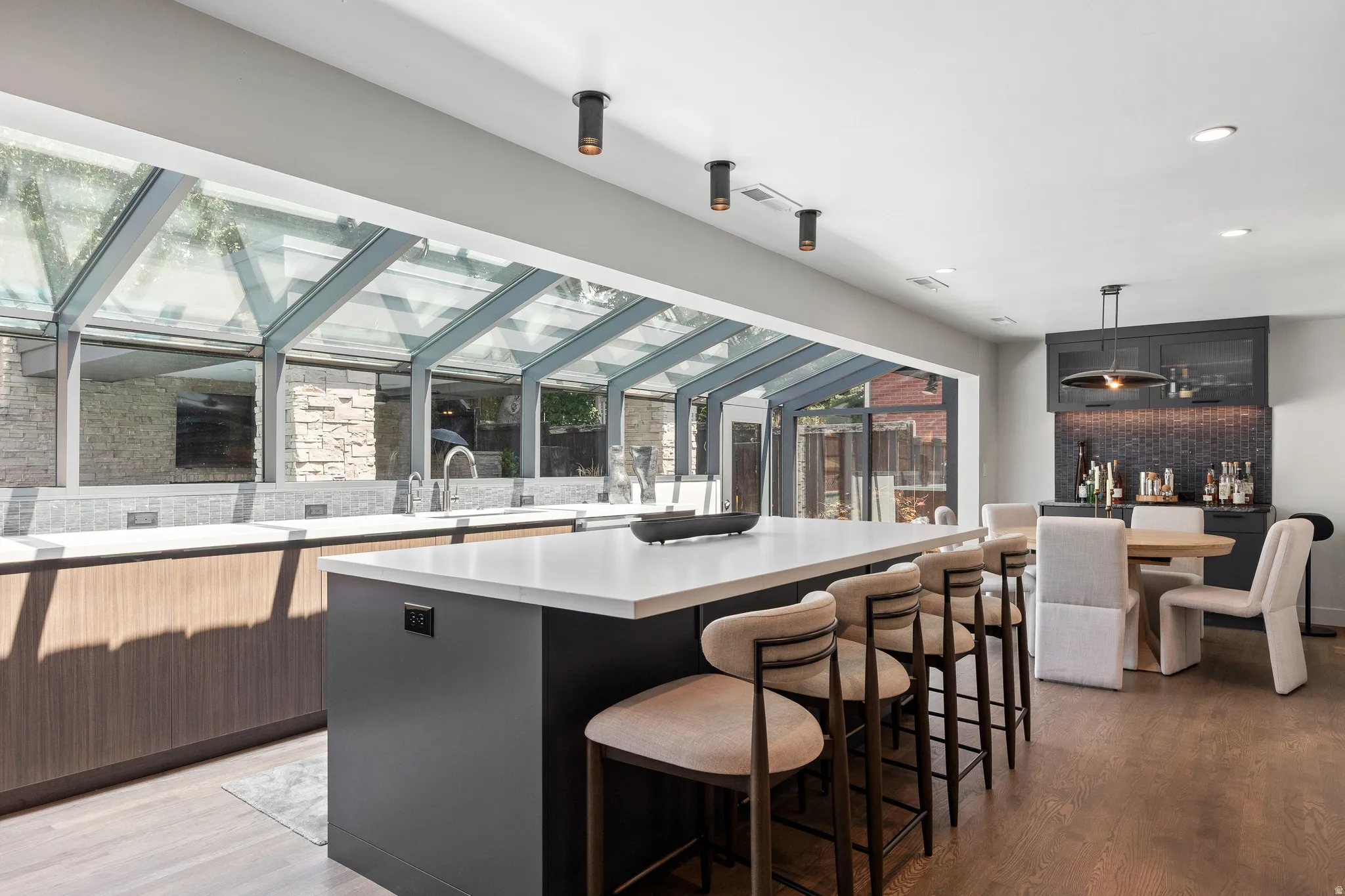 Kitchen featuring a large central island with seating, a built-in wet bar with cabinetry, and a full-wall glass enclosure