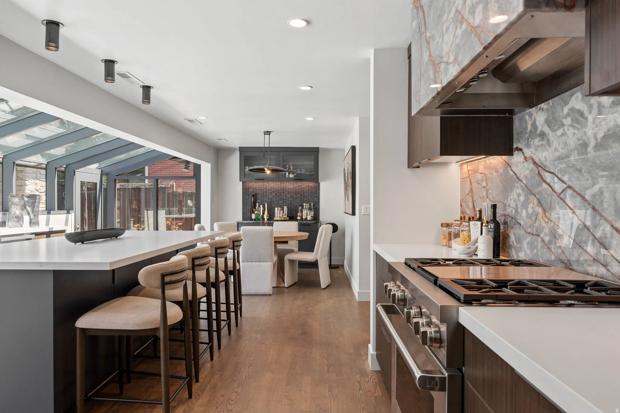 Contemporary kitchen featuring a large island with seating, stainless steel gas range, and stone slab backsplash