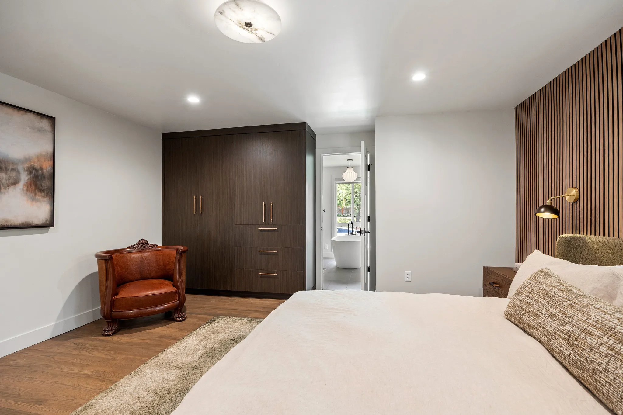 Wood-finish flooring, recessed lighting, and a built-in wardrobe with bronze hardware