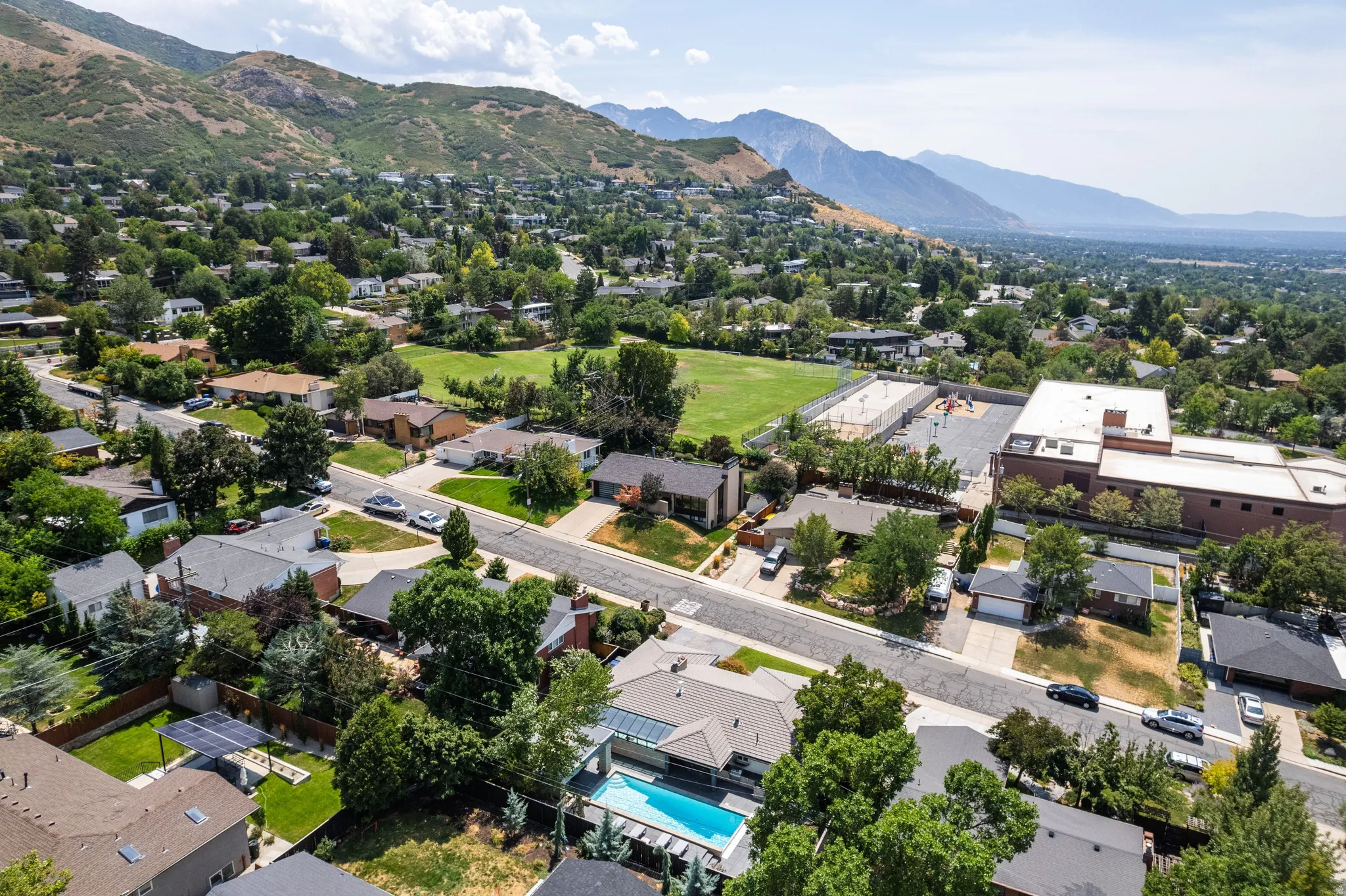 Residential neighborhood with varied architectural styles, established trees, and mountainous terrain