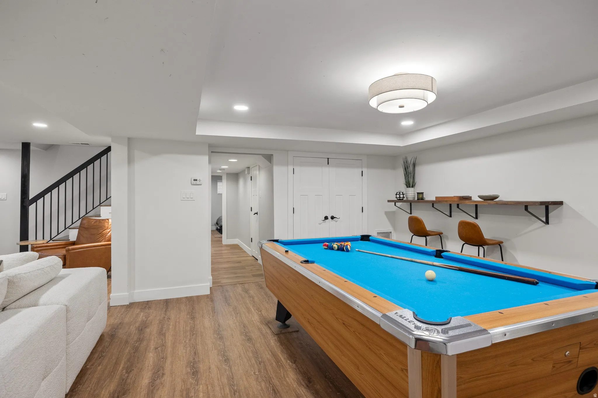 Wood-finish flooring throughout, featuring recessed lighting and a contemporary ceiling fixture