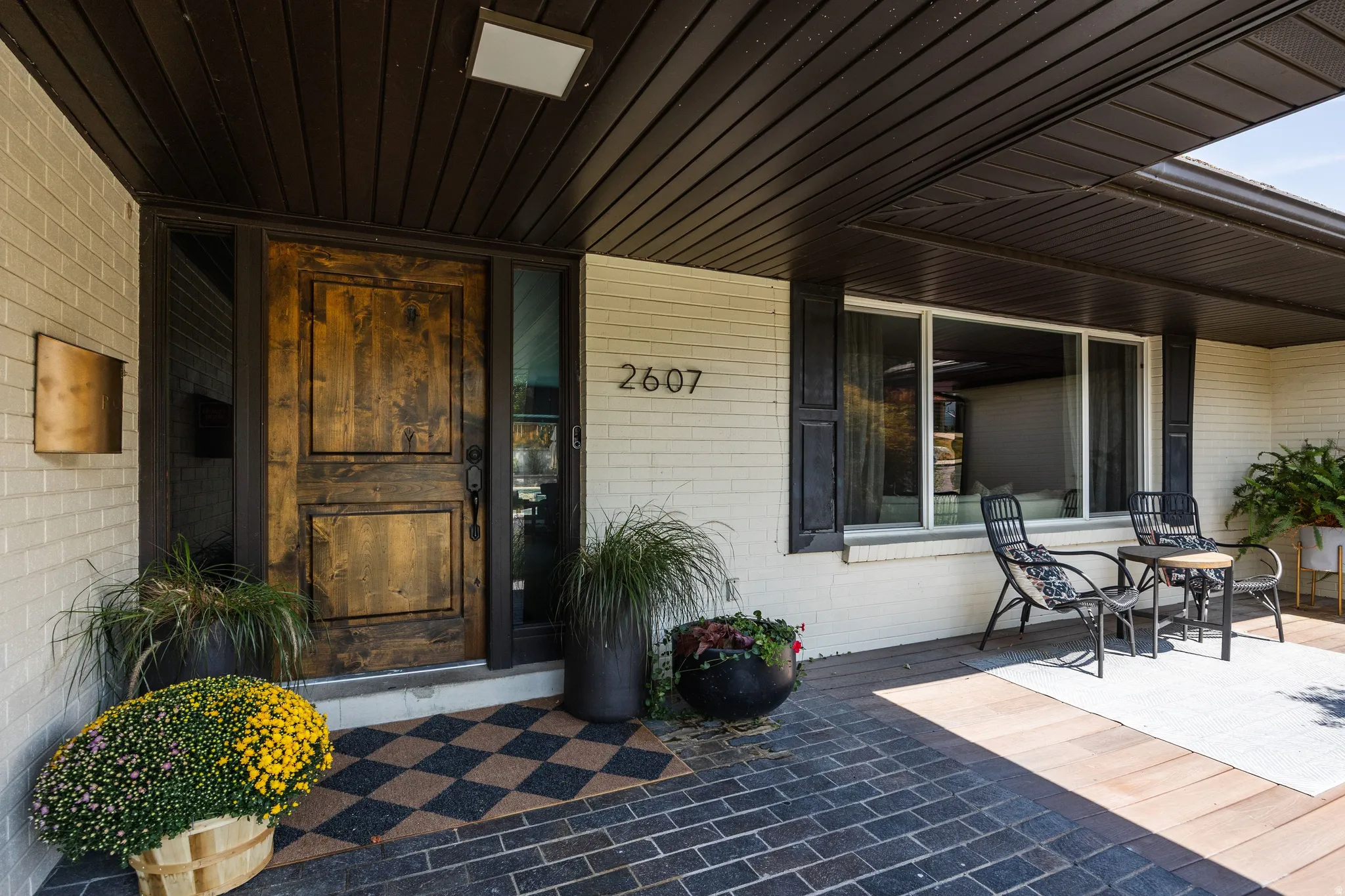 Brick facade with a prominent wood-panel door, sheltered by a dark wood-finish soffit