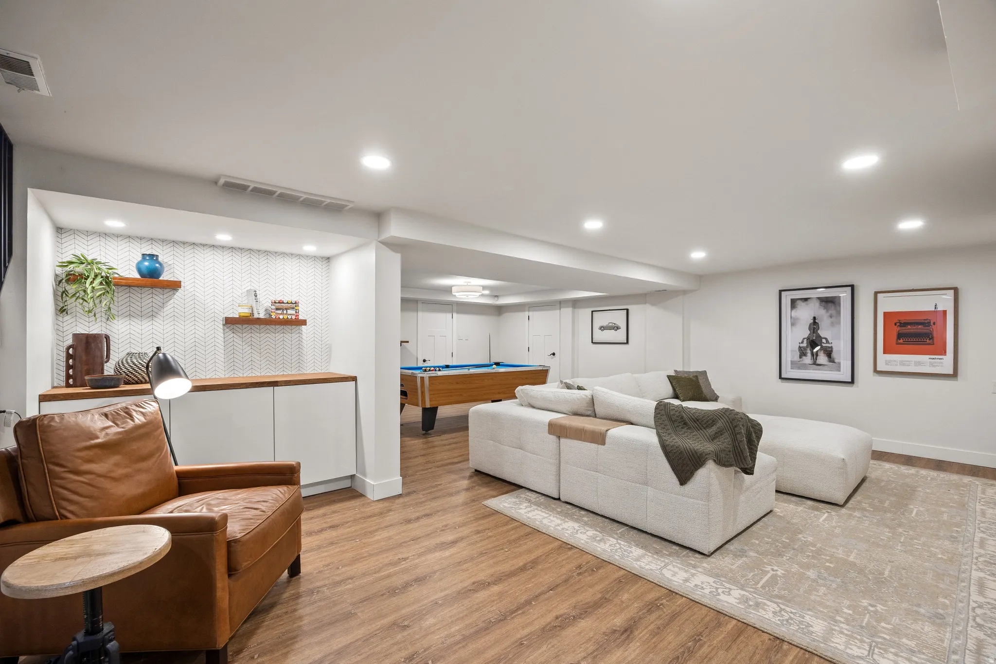 Recessed lighting throughout, wood-finish flooring, built-in cabinetry with wood countertops, and a decorative tile accent wall