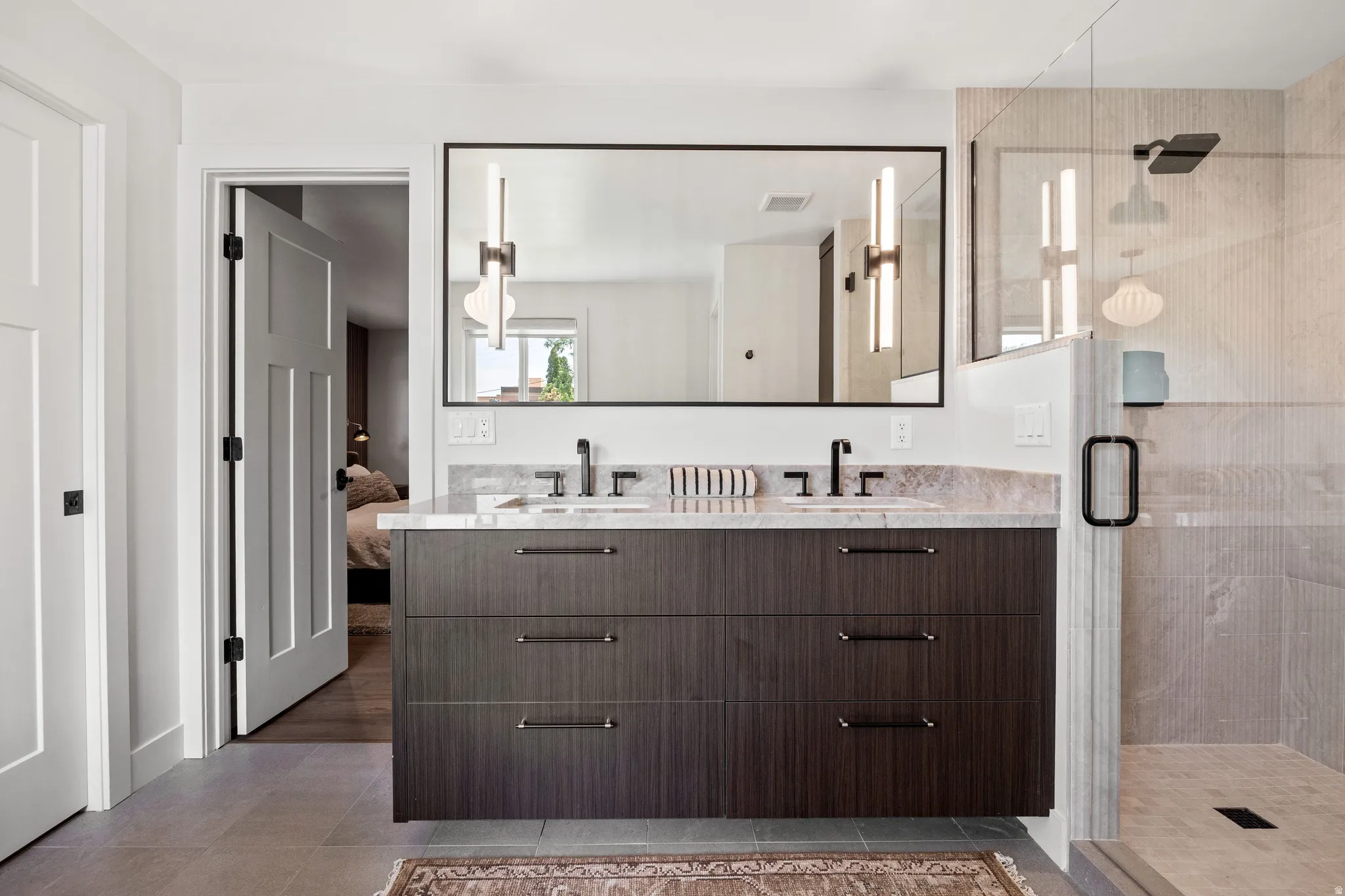 Floating dual vanity with rich wood-finish cabinetry and stone countertop