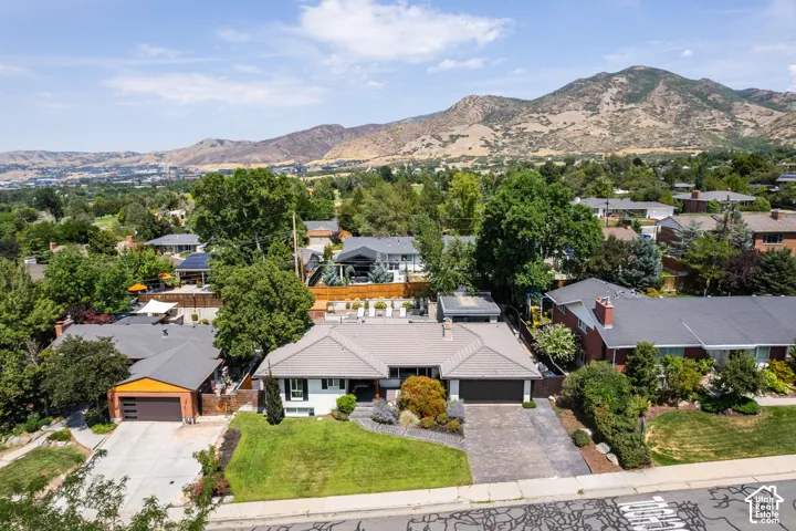 Mountain backdrop, residential neighborhood, mature trees, paved driveway, landscaped front yard