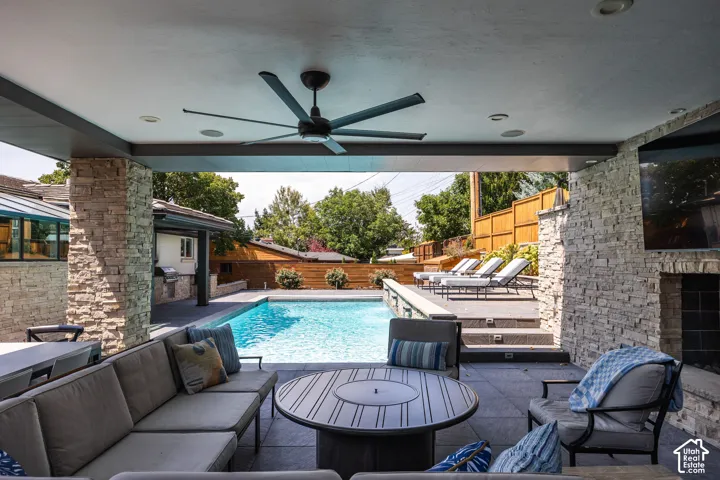 Covered outdoor patio with a ceiling fan, recessed lighting, and stone-clad columns