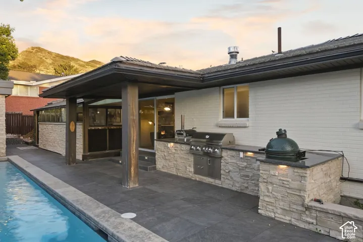 Outdoor kitchen with a built-in grill, stone-finish base, and dark countertops