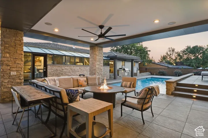 Covered outdoor patio featuring stone columns, recessed lighting, and a ceiling fan