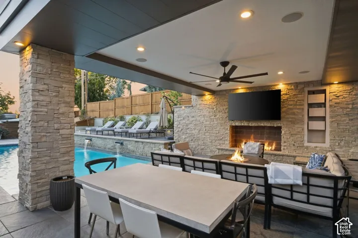 Covered outdoor living space featuring stone-clad columns and a recessed ceiling with lighting