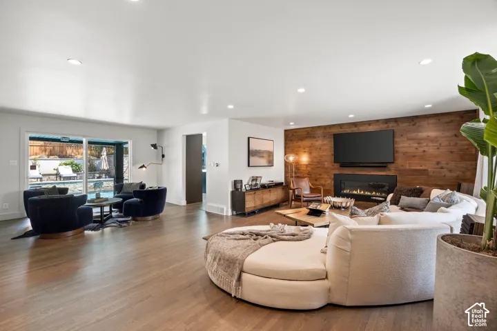 Hardwood-finish flooring throughout, recessed ceiling lighting, and a modern fireplace integrated into a wood-paneled wall