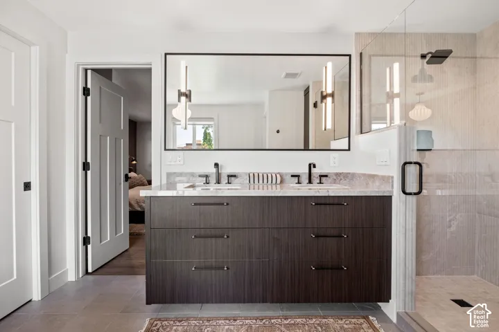Floating dual vanity with stone countertop, matte black fixtures, framed mirror, and glass-enclosed shower