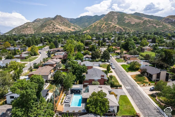 Rectangular swimming pool with integrated spa and lounge seating, surrounded by mature trees, with mountain scenery