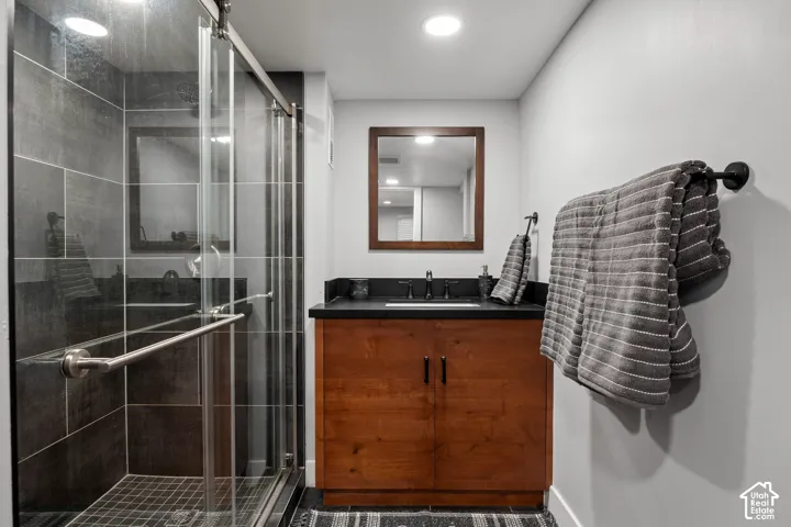 Shower with dark large-format tile surround, glass enclosure, and a chrome grab bar
