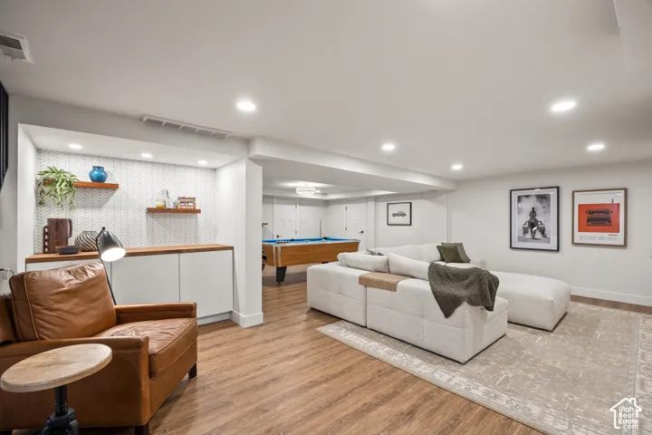 Recessed lighting throughout, wood-finish flooring, built-in cabinetry with wood-finish countertops, and a decorative tile backsplash