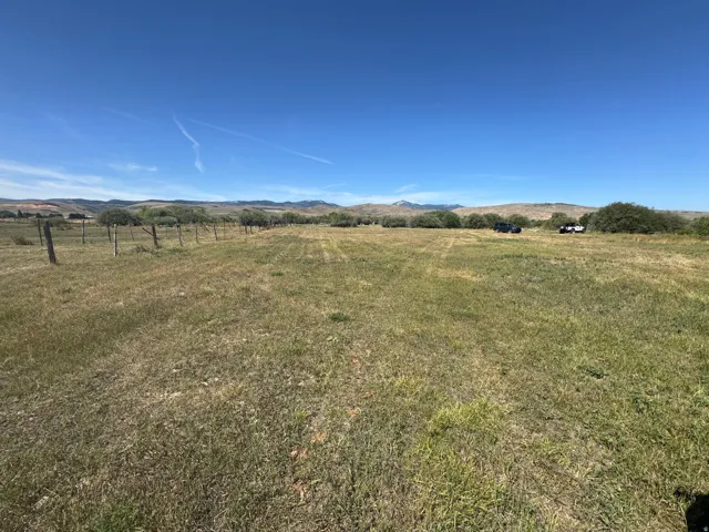 Expansive open land featuring a wire fence and natural terrain