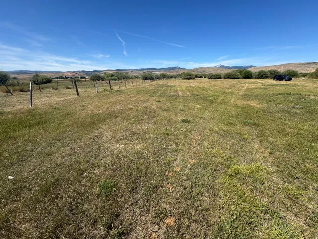 Expansive undeveloped land featuring natural grasses and distant mountains under a clear sky