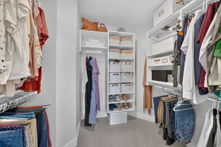 Custom closet system featuring white shelving, multiple hanging rods, and integrated shoe storage