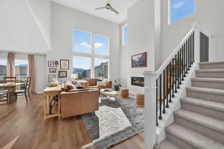 Two-story living area with high ceilings, featuring wood-finish flooring, a contemporary fireplace, and large windows