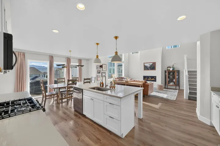 Open-concept living space featuring wood-finish flooring, a kitchen island with sink and stainless steel appliances, and a gas cooktop