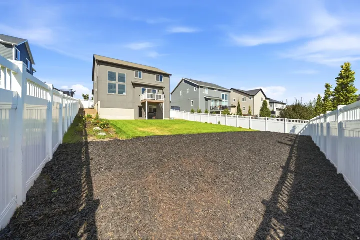 Expansive backyard featuring a large mulched area, a lush green lawn, and full privacy fencing